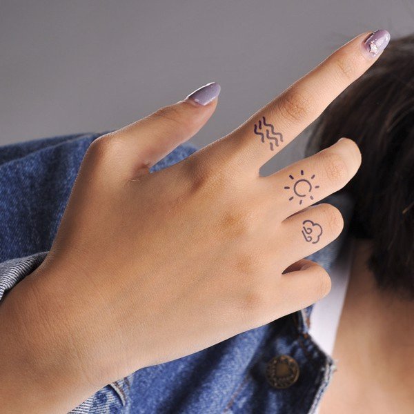 B&agrave;n tay với m&oacute;ng tay sơn m&agrave;u t&iacute;m v&agrave; h&igrave;nh xăm nhỏ tr&ecirc;n hai ng&oacute;n tay.