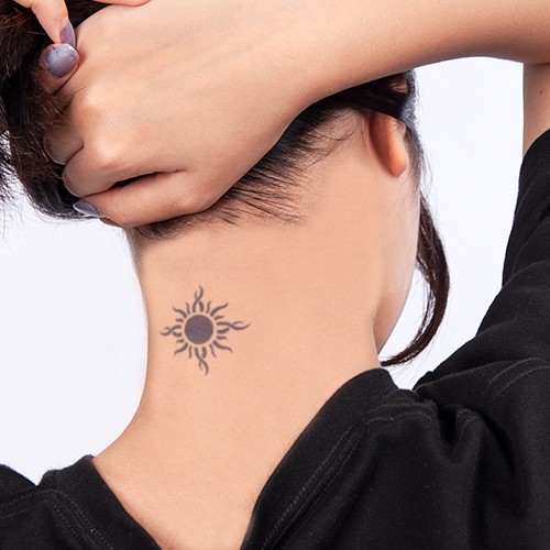 Người đang v&eacute;n t&oacute;c, để lộ h&igrave;nh xăm mặt trời ở ph&iacute;a sau g&aacute;y, mặc &aacute;o đen.