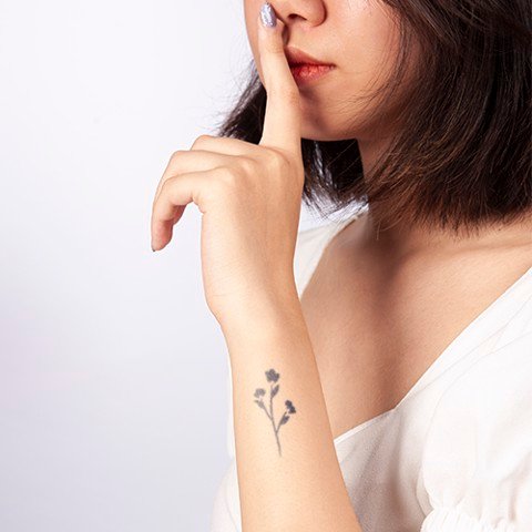 cach-tu-xam-hinh-don-gian-6_0b73d2da3b9849f089c639961d392eab_large Người giơ ngón trỏ lên môi biểu thị im lặng, trên cánh tay có hình xăm hoa, mặc áo trắng.