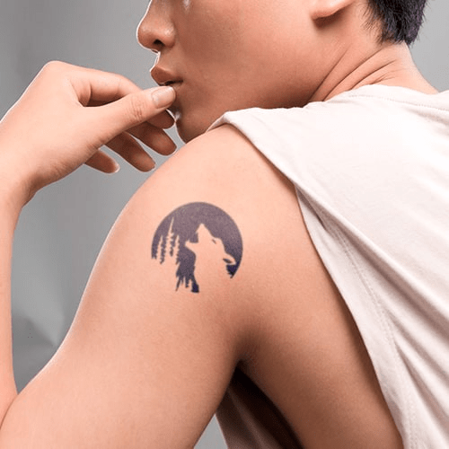 Người mặc áo khoét nách, có hình xăm sói tru trước mặt trăng và rừng cây trên vai.