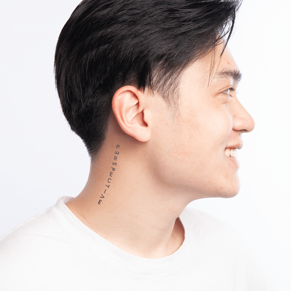 Một người mặc áo trắng, nhìn ngang, có hình xăm chữ "PERSPECTIVE" ở cổ, nền trắng.