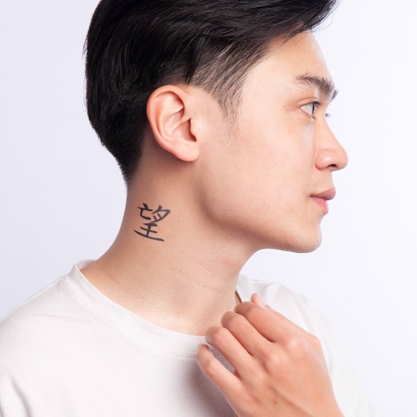 Người đàn ông nhìn nghiêng, có hình xăm chữ Trung Quốc trên cổ, mặc áo phông trắng, nền trắng.