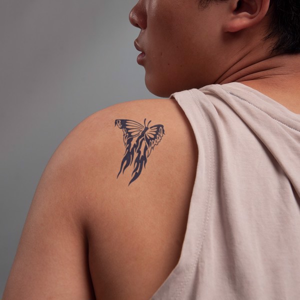 Người mặc áo ba lỗ, trên vai có hình xăm bướm với họa tiết lửa màu đen.