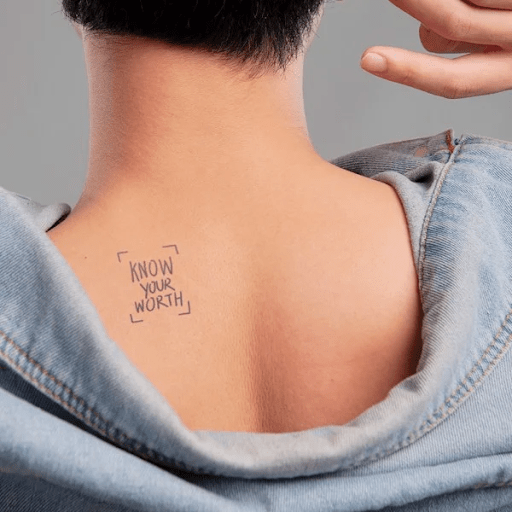 Người mặc áo khoác hở vai, để lộ hình xăm "KNOW YOUR WORTH" trên lưng dưới.