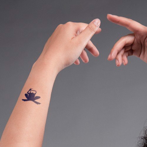 Tay trái có hình xăm người ngồi thiền, tay phải từ phía trên đưa xuống, nền xám.