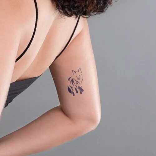 Một hình xăm hình con sói trên cánh tay của một người mặc áo dây đen.