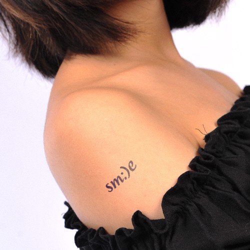 Hình xăm chữ "smile" trên vai người mặc áo đen, tóc ngắn.