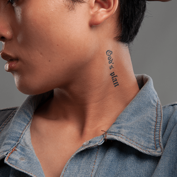 Cận cảnh một người với hình xăm trên cổ, mặc áo denim, nhìn sang trái.