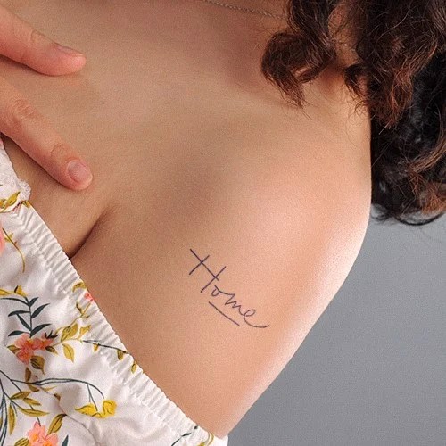 Vai người với hình xăm chữ "Home" và một phần áo hoa.