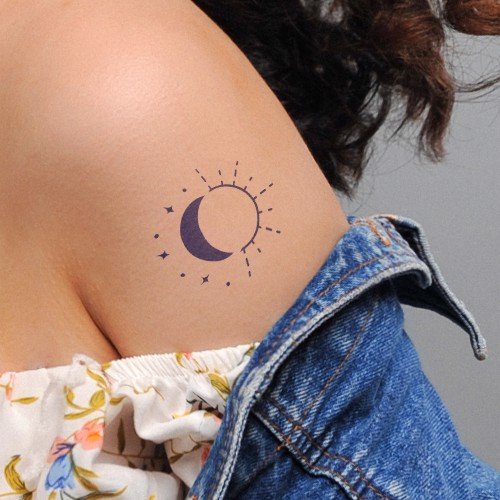 Vai người với hình xăm mặt trăng và sao, mặc áo trễ vai hoa và áo khoác denim.