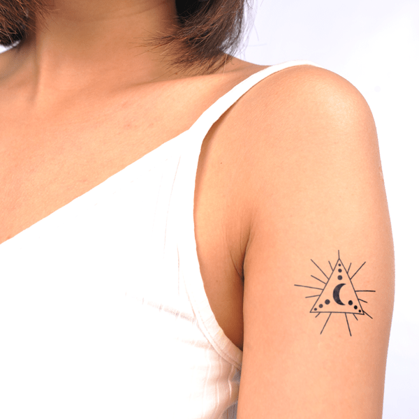 Người mặc áo trắng, xăm hình tam giác với mặt trăng và các chấm tròn trên cánh tay.