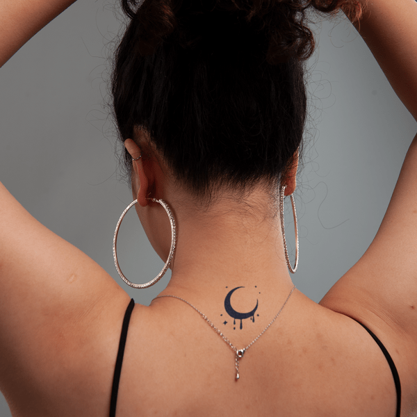 Người đang buộc tóc, đeo khuyên tai lớn và có hình xăm mặt trăng sau gáy.