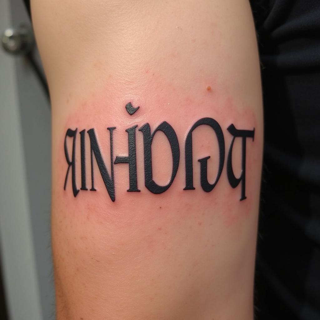 Hình xăm số La Mã màu đen trên bắp tay nam, phong cách cổ điển.